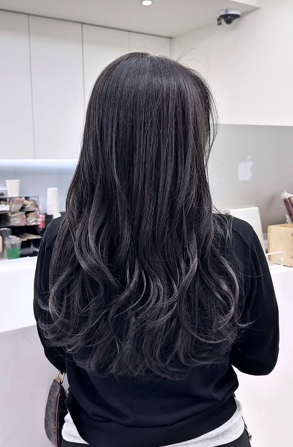 A woman with long black hair is standing in a room.