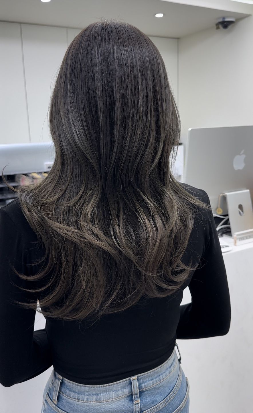 A woman with long hair is wearing a black shirt and blue jeans.