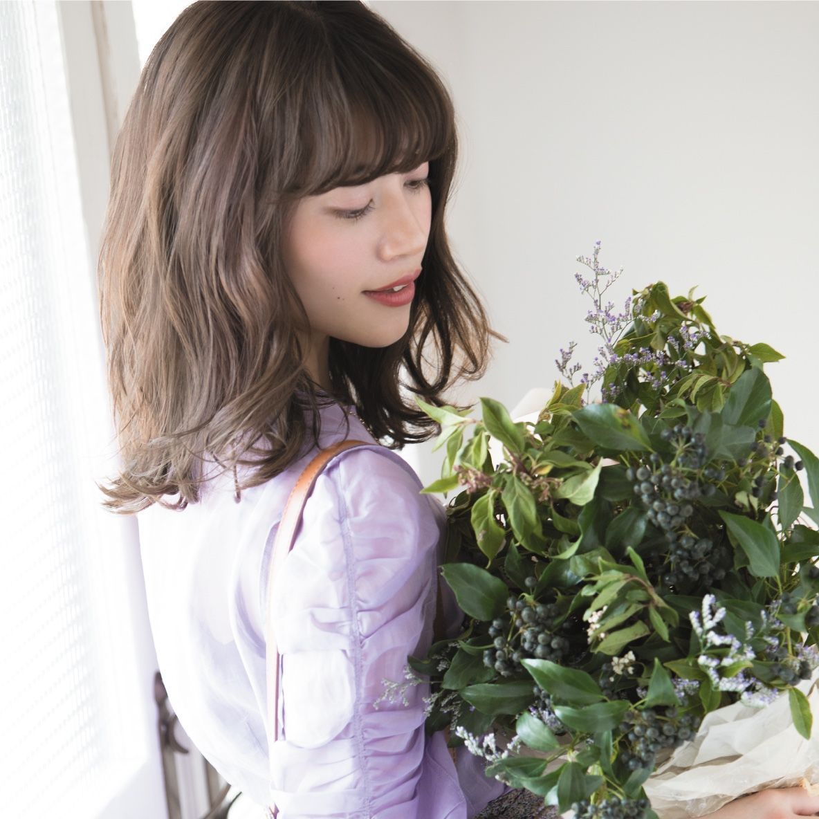 A woman in a purple shirt is holding a bouquet of flowers