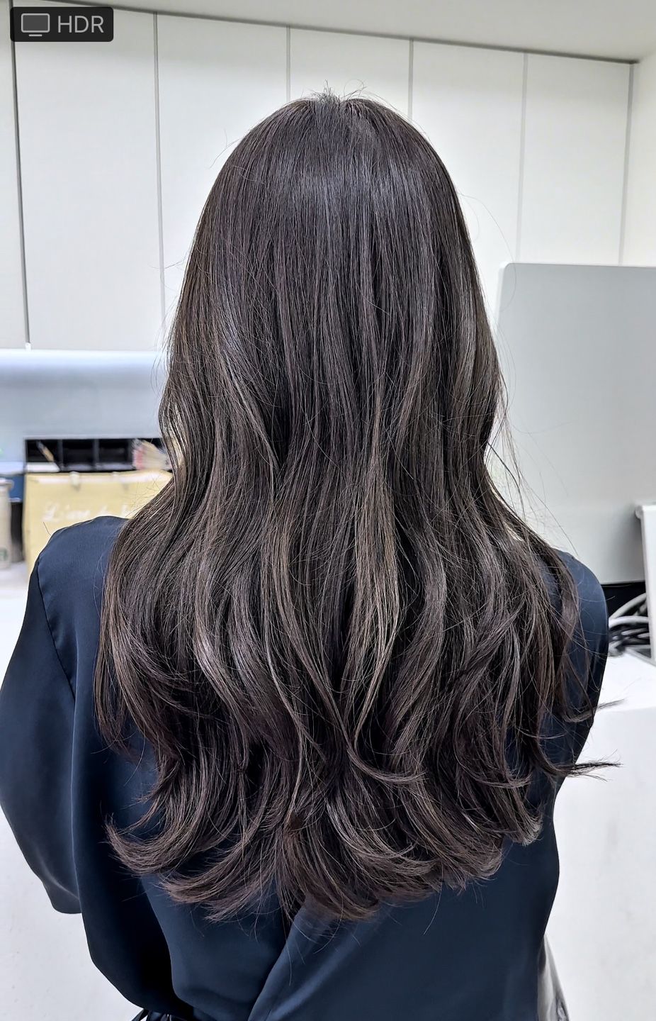 A woman with long brown hair is standing in a room.