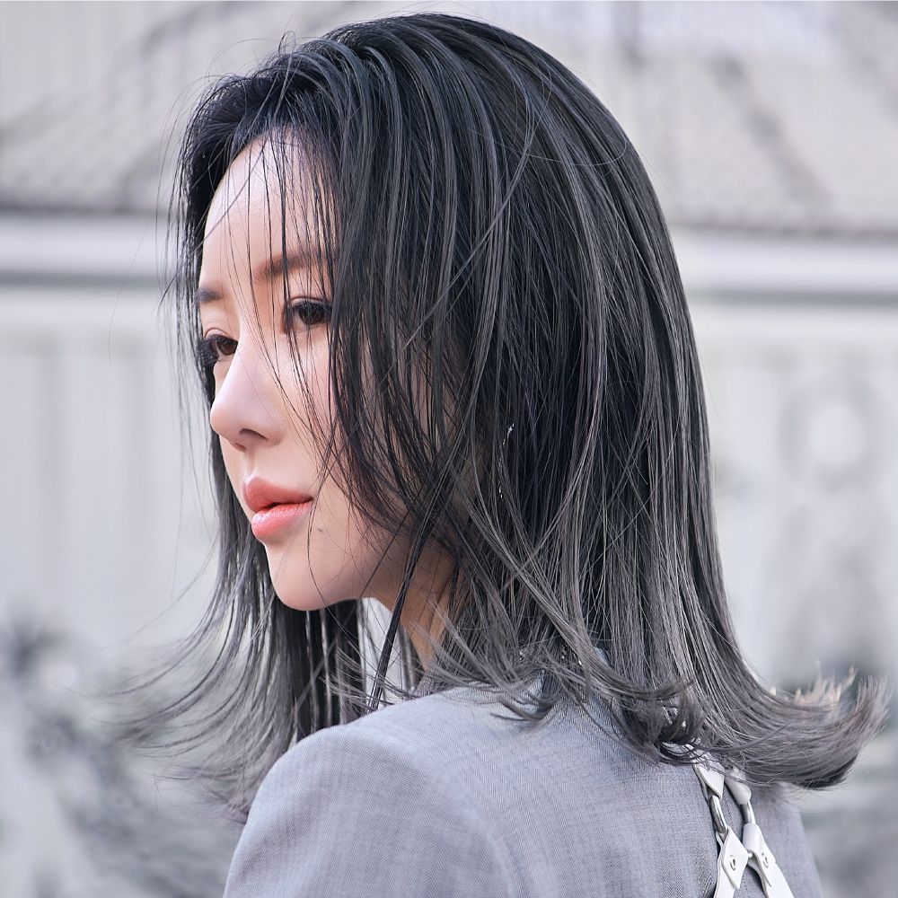 A woman with long black hair is looking over her shoulder.