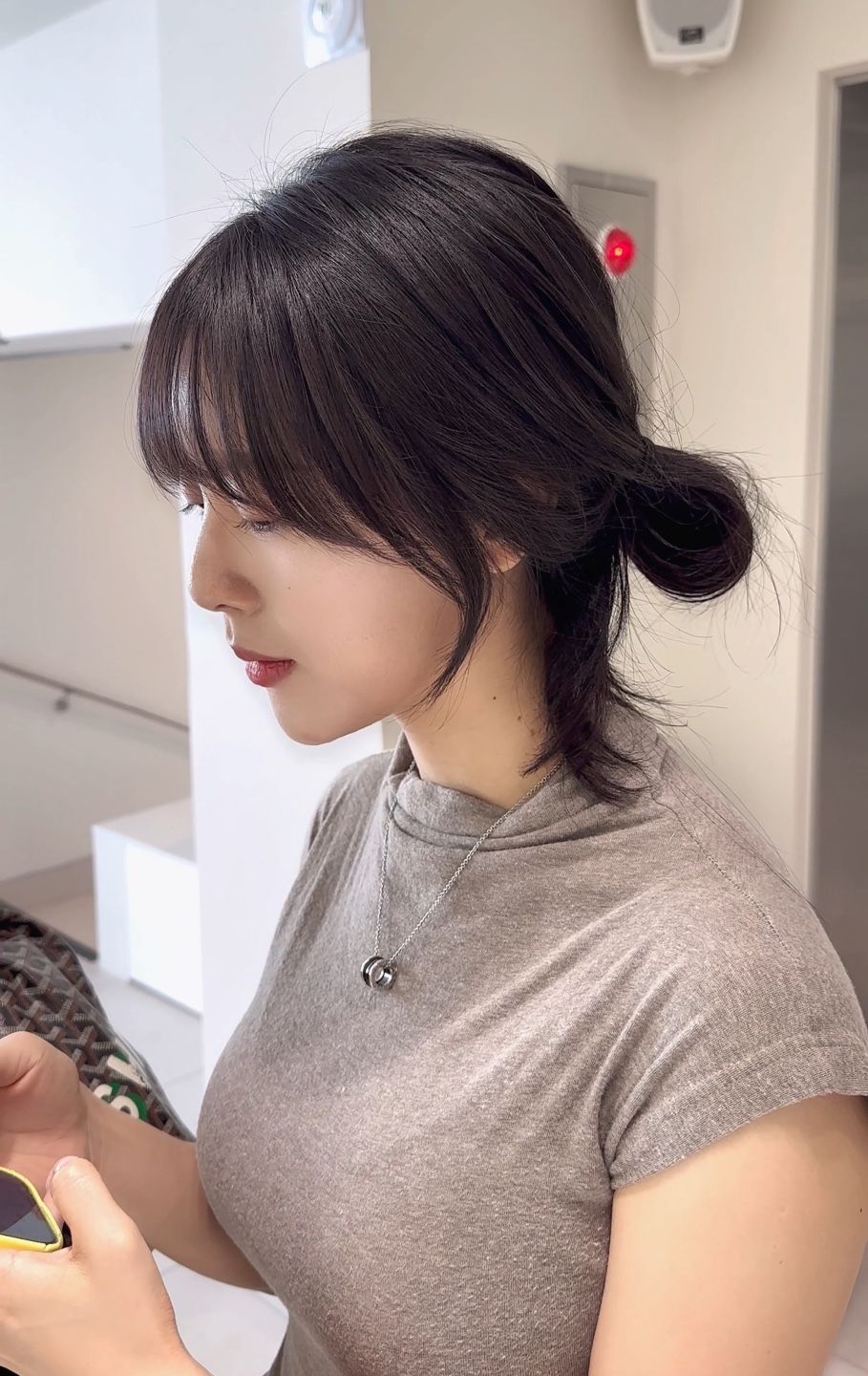 A woman with her hair in a bun is looking at her phone.