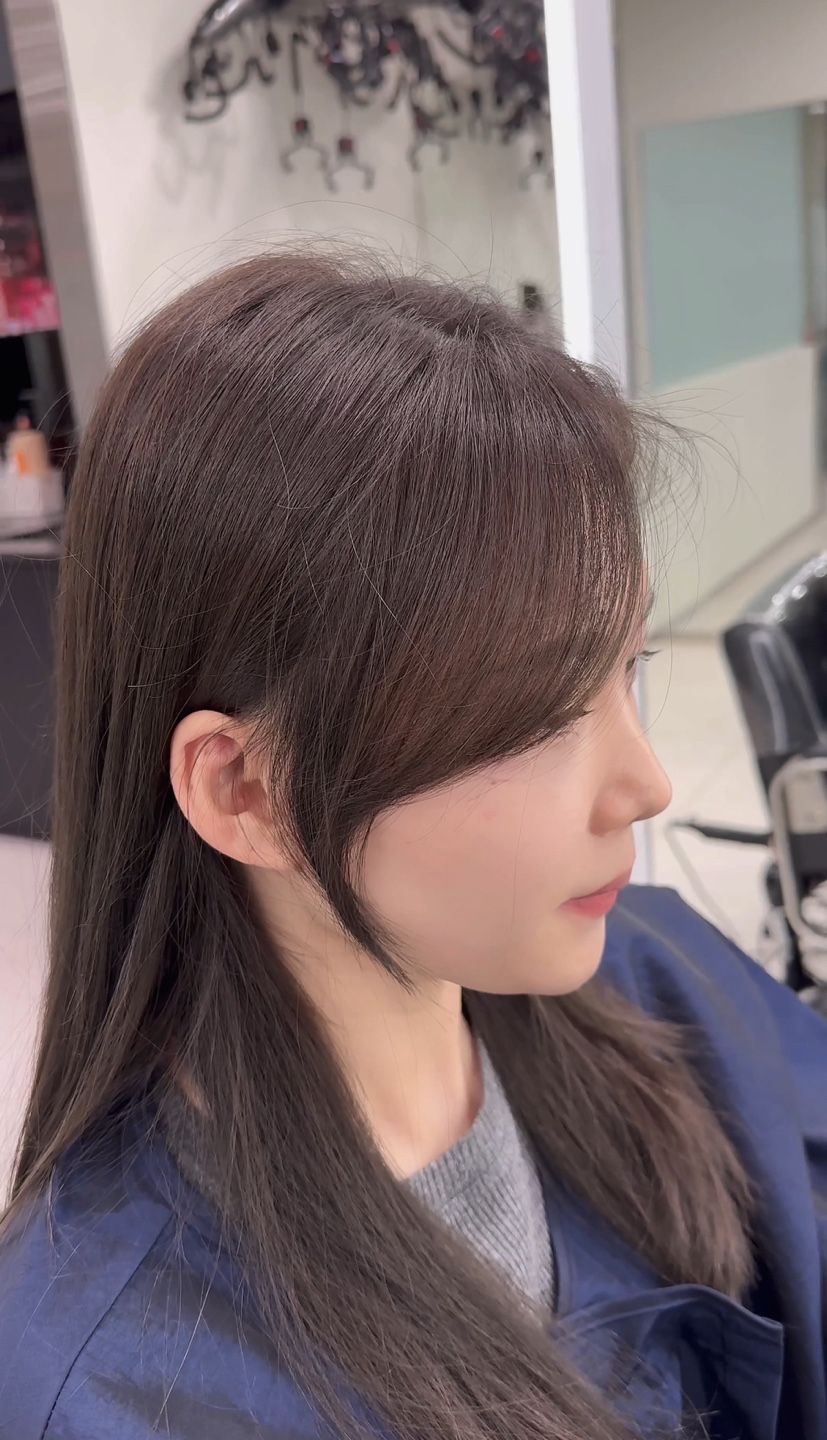 A woman with long hair is sitting in a chair in a salon.