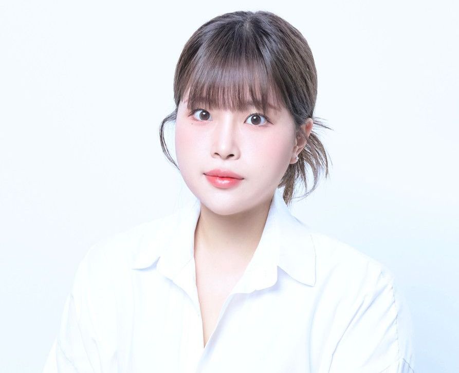 A woman in a white shirt is looking at the camera.