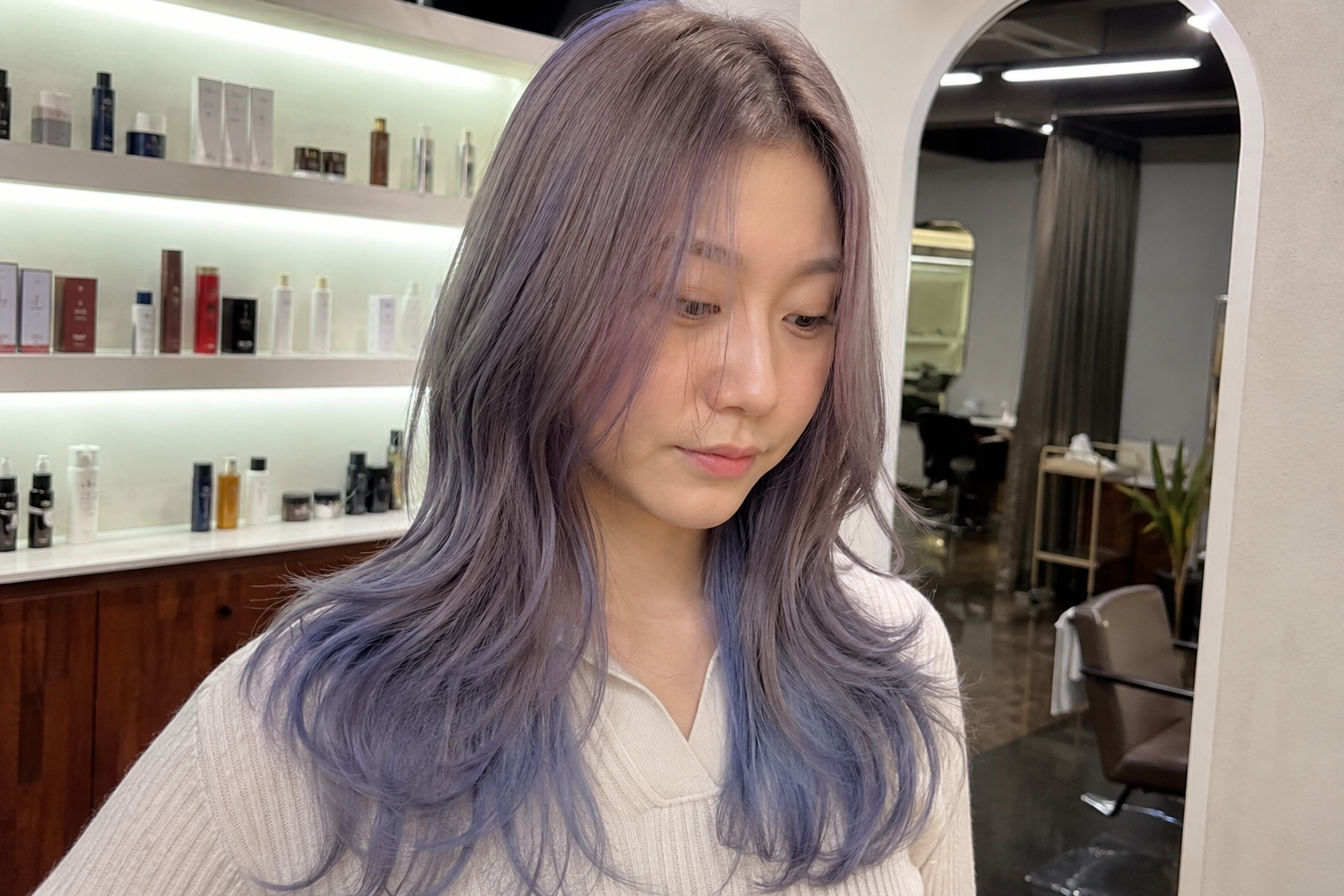 A woman with long hair is sitting in a chair at a hair salon.