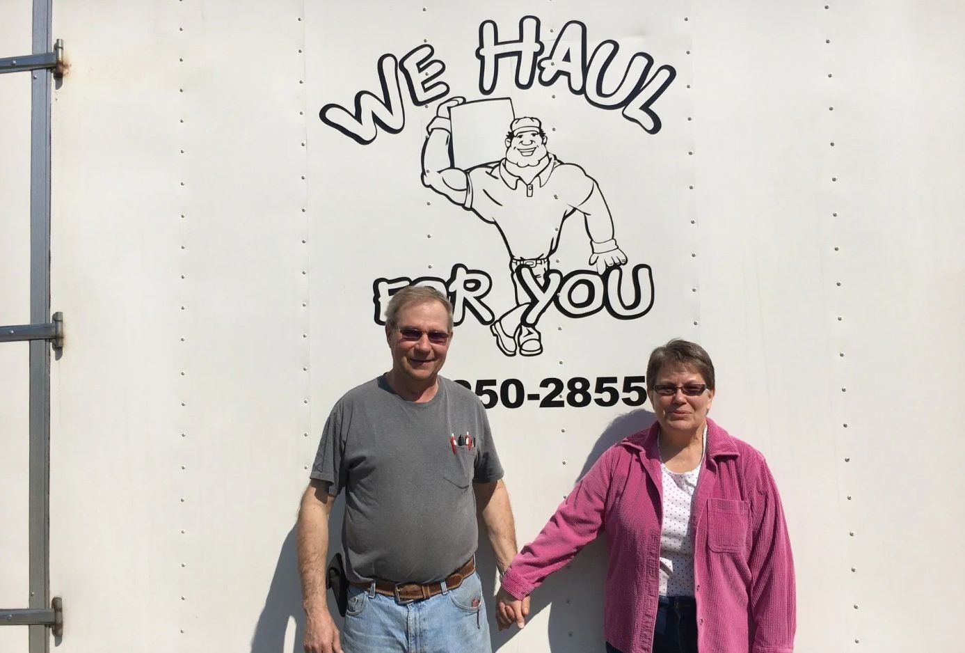 Couple standing in front of a truck with a logo that says,