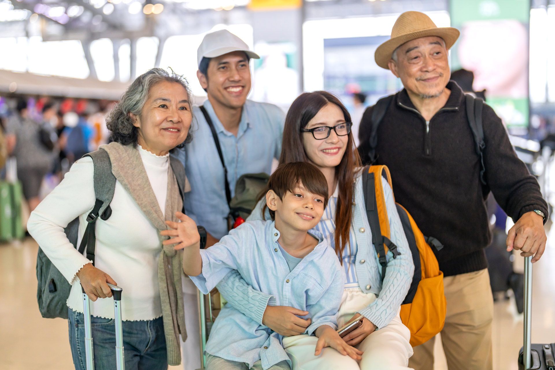 Family smiling at airport, holding luggage.