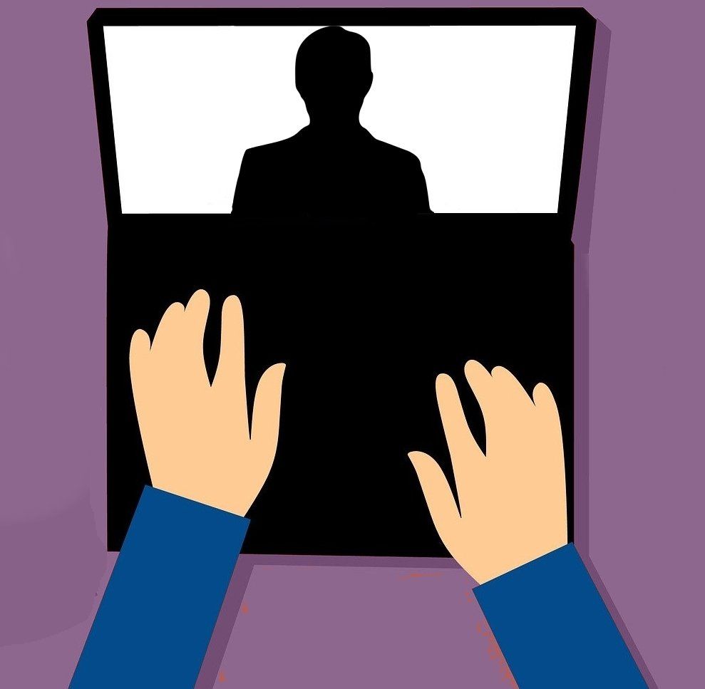 Hands on a laptop with a silhouetted person on screen