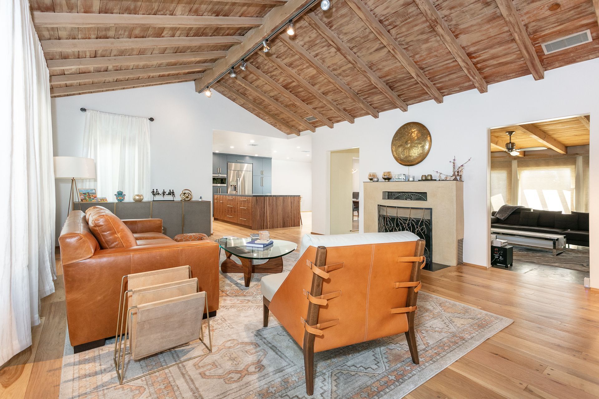 Living room with brown leather furniture, wooden ceiling, fireplace, and hardwood floors.
