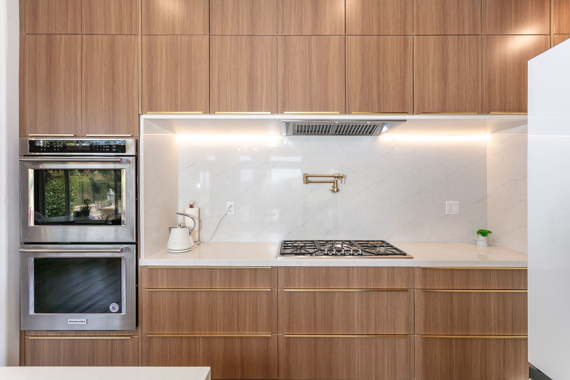 Modern kitchen with wood cabinets, a stainless steel oven, and a cooktop with a backsplash.