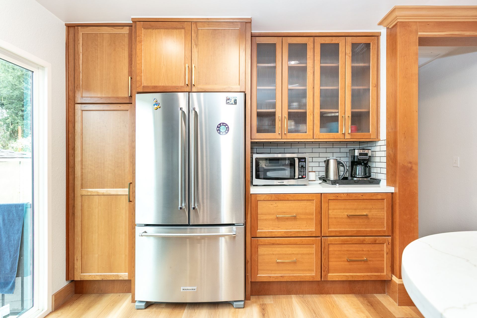 Kitchen with stainless steel refrigerator, wood cabinets, microwave, and coffee maker.