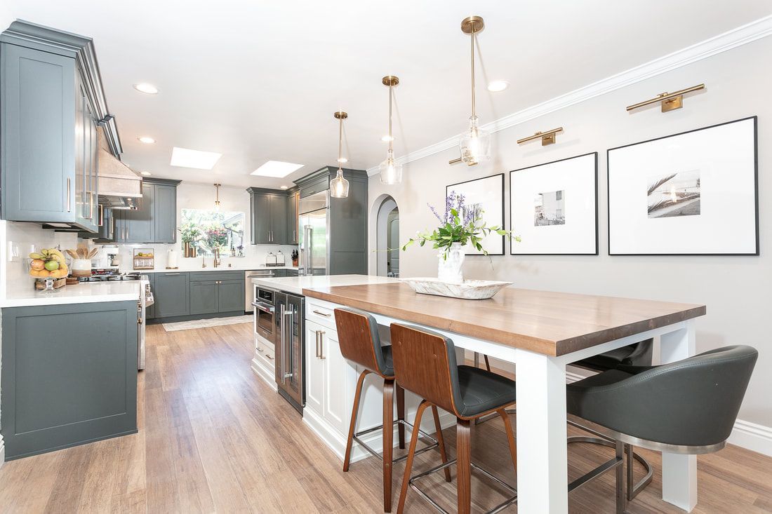 Spacious, modern kitchen with gray cabinets, wood island, and three framed photos.