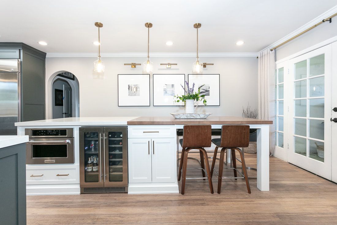 Modern kitchen with white cabinets, wood island, and hanging gold lights.