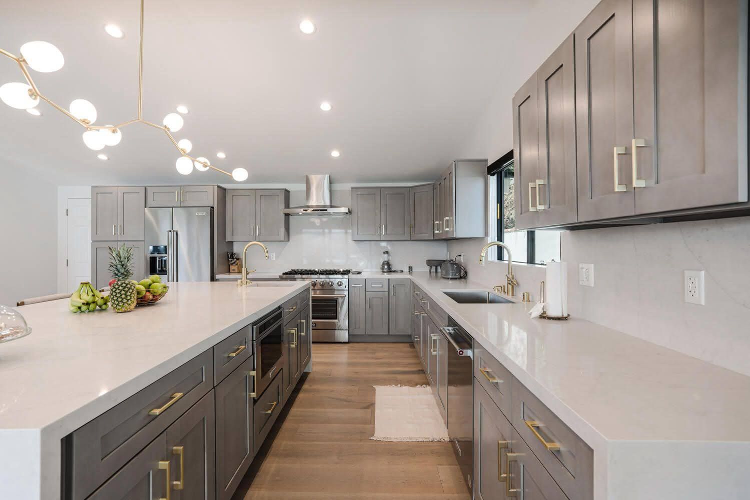 Gray kitchen with a large island and cabinets. White countertops and gold hardware.