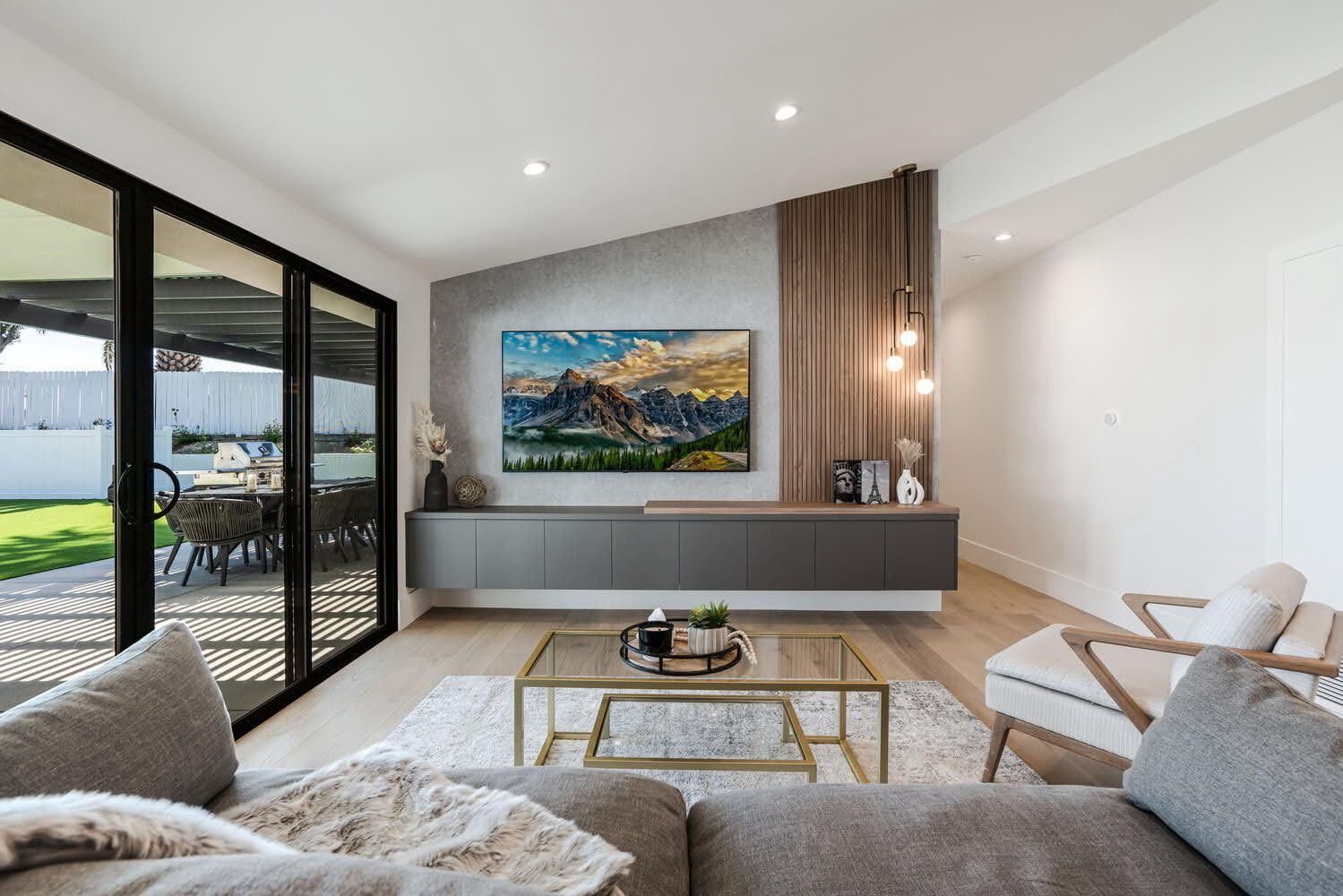 Modern living room with a view of the backyard, featuring a TV, sectional sofa, and coffee table.