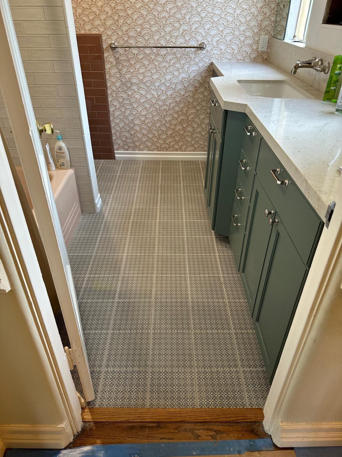 Bathroom with patterned tile floor, blue cabinets, and a floral-patterned wall.