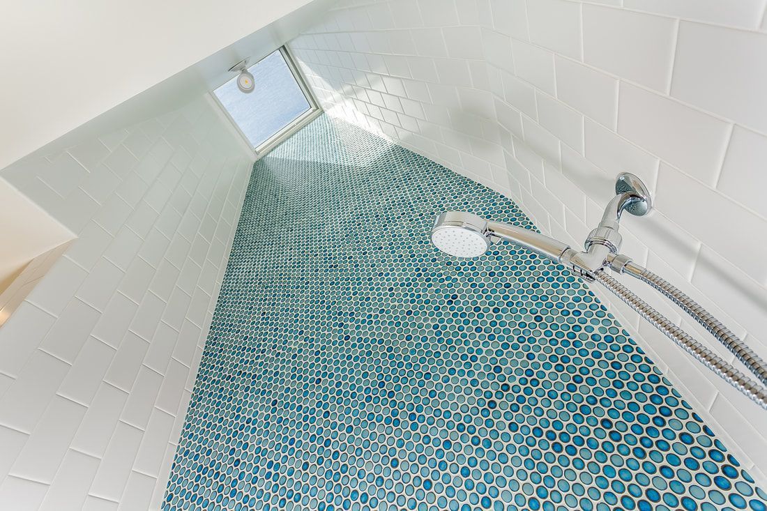 Shower with blue mosaic accent wall, white tiles, and a skylight.