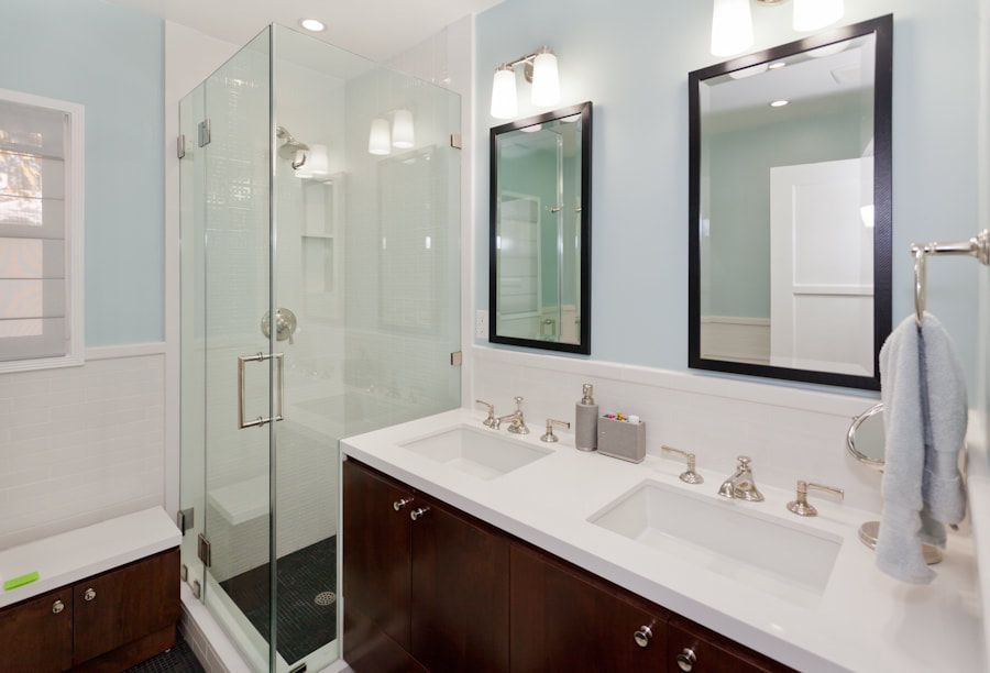 Bathroom with blue walls, a glass shower, dark wood vanity, and two white sinks.
