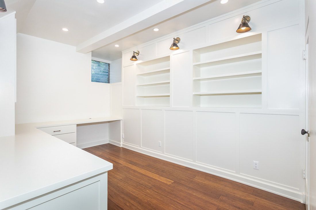 Bright white office space with built-in shelves, desk, and hardwood floor.