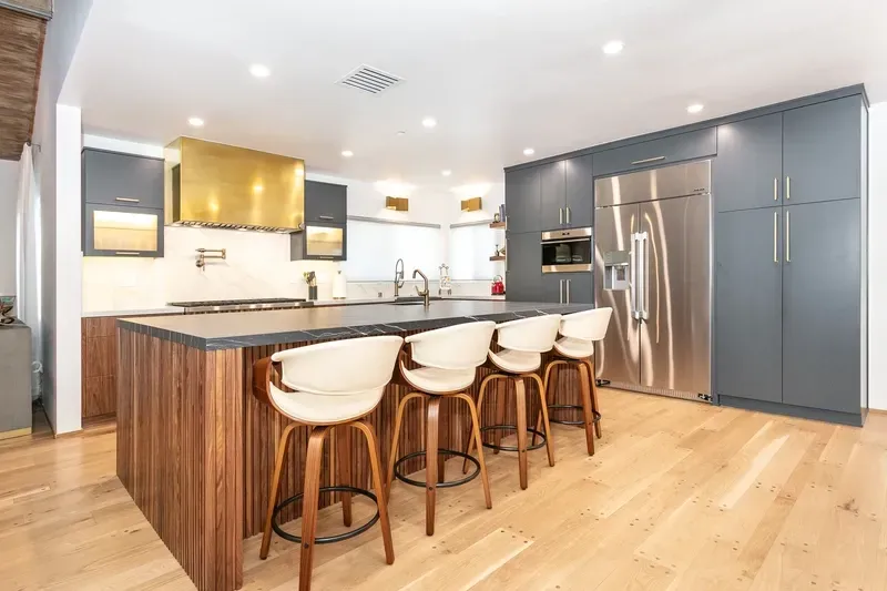 Modern kitchen with wooden island, stainless steel appliances, and gray cabinets.