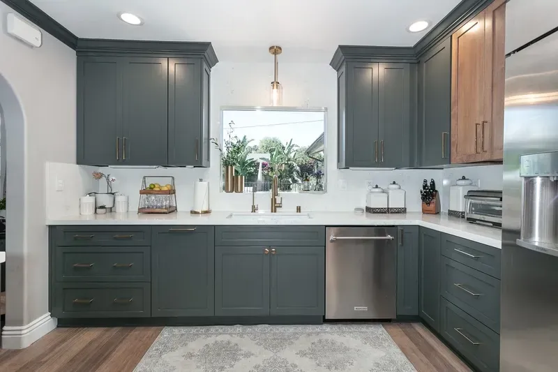 Gray and wood-toned kitchen with dark cabinets, white countertops, and stainless steel appliances.