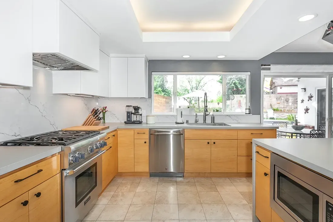 Modern kitchen with wood cabinets, stainless steel appliances, and a skylight.