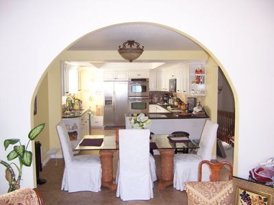 Dining room with table and chairs, arched opening to kitchen.