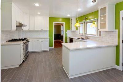 White kitchen with lime green walls, gray floor, and white cabinets.
