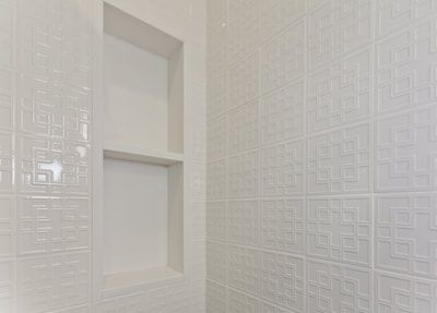 White tiled shower with built-in storage shelves.