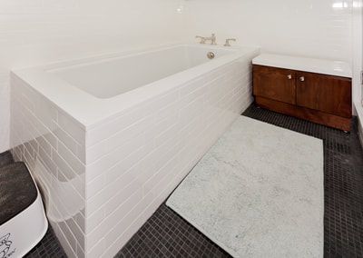 Modern white bathroom with a tub, vanity, and dark tiled floor.