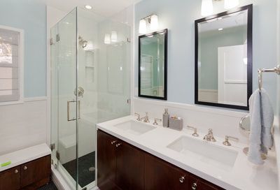Modern bathroom with glass shower, double sink, and blue walls.