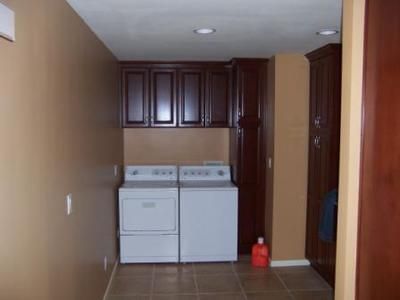 Laundry room with washer, dryer, dark cabinets, and brown walls.