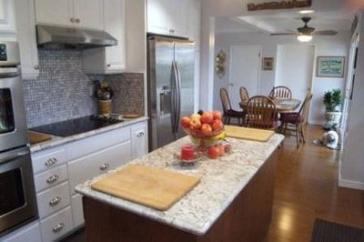 Kitchen with white cabinets, island, stainless steel appliances, and open dining area.