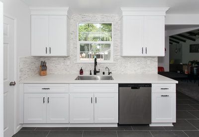 White kitchen with matching cabinets, stainless steel appliances, and a window.