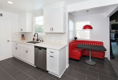 White kitchen with stainless steel appliances, dark gray tiled floor, and a red diner booth.