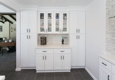 White kitchen cabinets with glass-fronted upper cabinets, a countertop, and dark tiled floor.