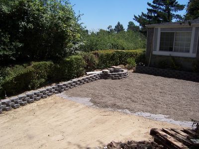 Backyard with gravel, retaining walls, and a fire pit.