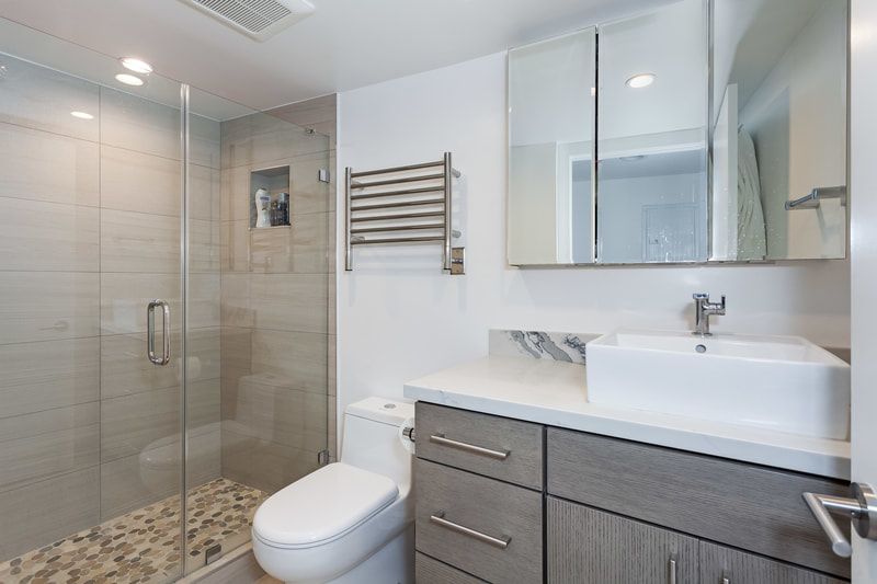 Modern bathroom with glass shower, floating vanity, and white toilet.