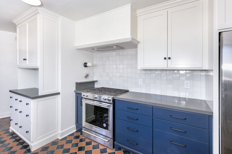 Kitchen with white upper cabinets, blue lower cabinets, and stainless steel appliances.