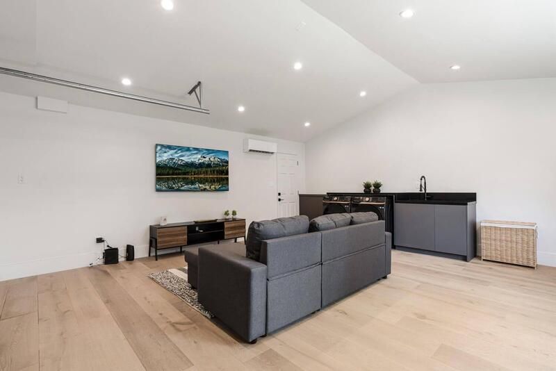 Modern living room with gray sofa, hardwood floors, and a small bar area.