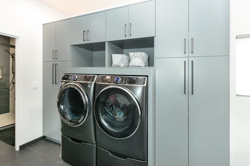 Modern laundry room with gray cabinets, washer, and dryer.