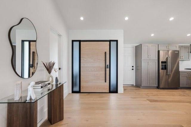 Entryway with a wood door, glass panels, hardwood floor, and console table with mirror.