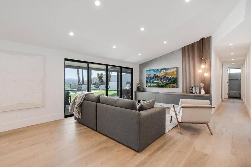 Modern living room with gray sofa, TV, and sliding glass doors.