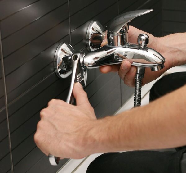 A person is fixing a radiator with a pair of pliers.