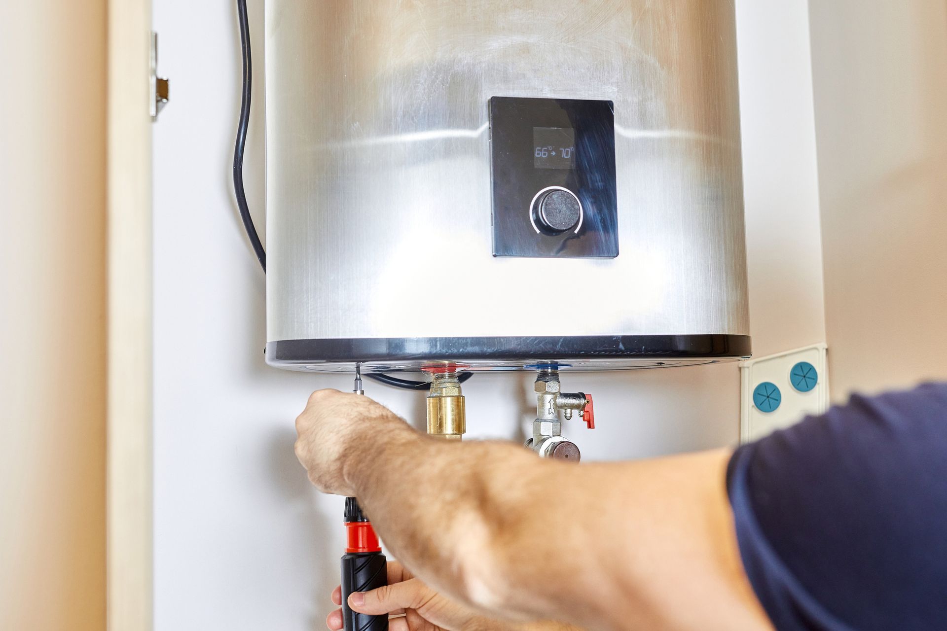 A man is fixing a water heater with a screwdriver.