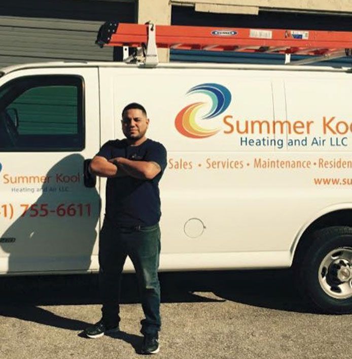 Man standing with arms crossed in front of a white Summer Kool van with ladder