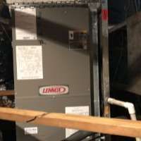 A Lennox furnace in a home's utility room, with attached pipes and wooden beams