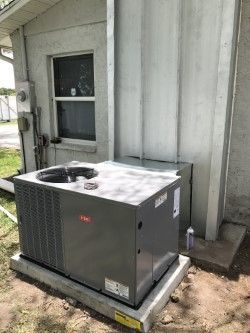 Gray Bryant air conditioner unit installed outside building on concrete pad