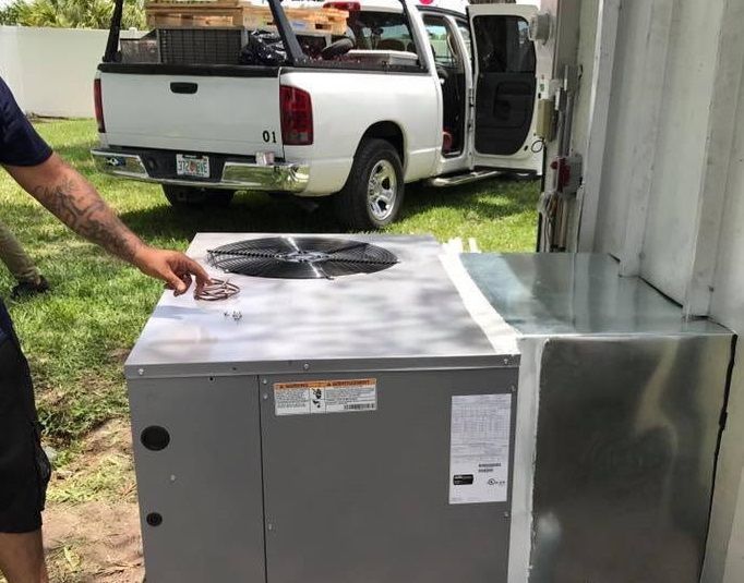 Man cleaning a new air conditioning unit near a white pickup truck