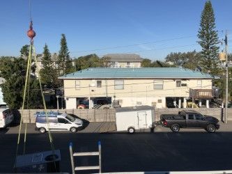 Crane lifting HVAC unit near a two-story building